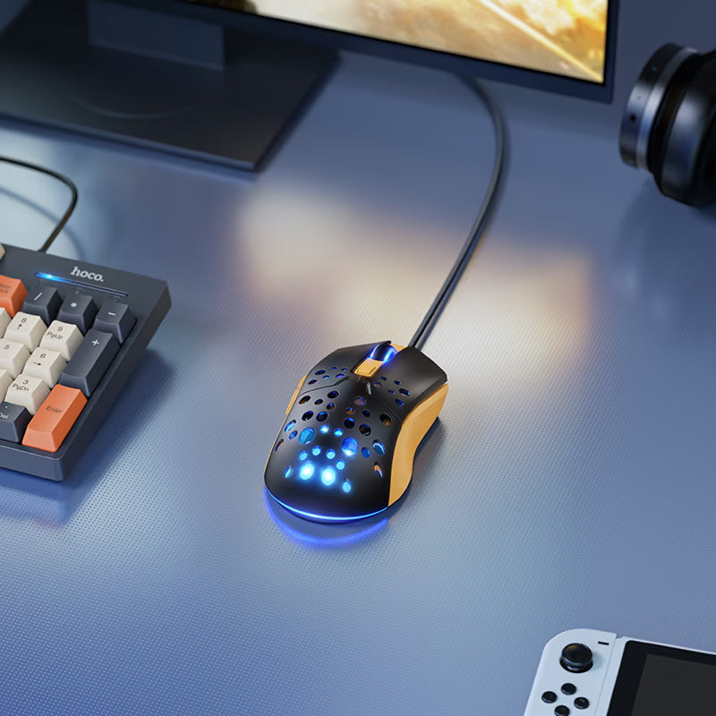 Mouse HOCO GM51 Sky negro y amarillo iluminado sobre un escritorio gamer
