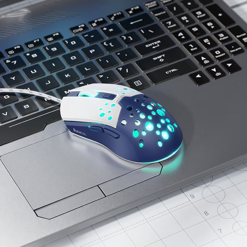 Mouse HOCO GM51 Sky blanco y azul en uso junto a un notebook