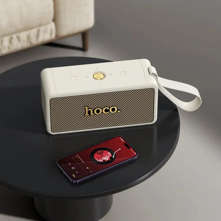 Parlante HOCO HT1 Max blanco sobre mesa de living junto a un reproductor